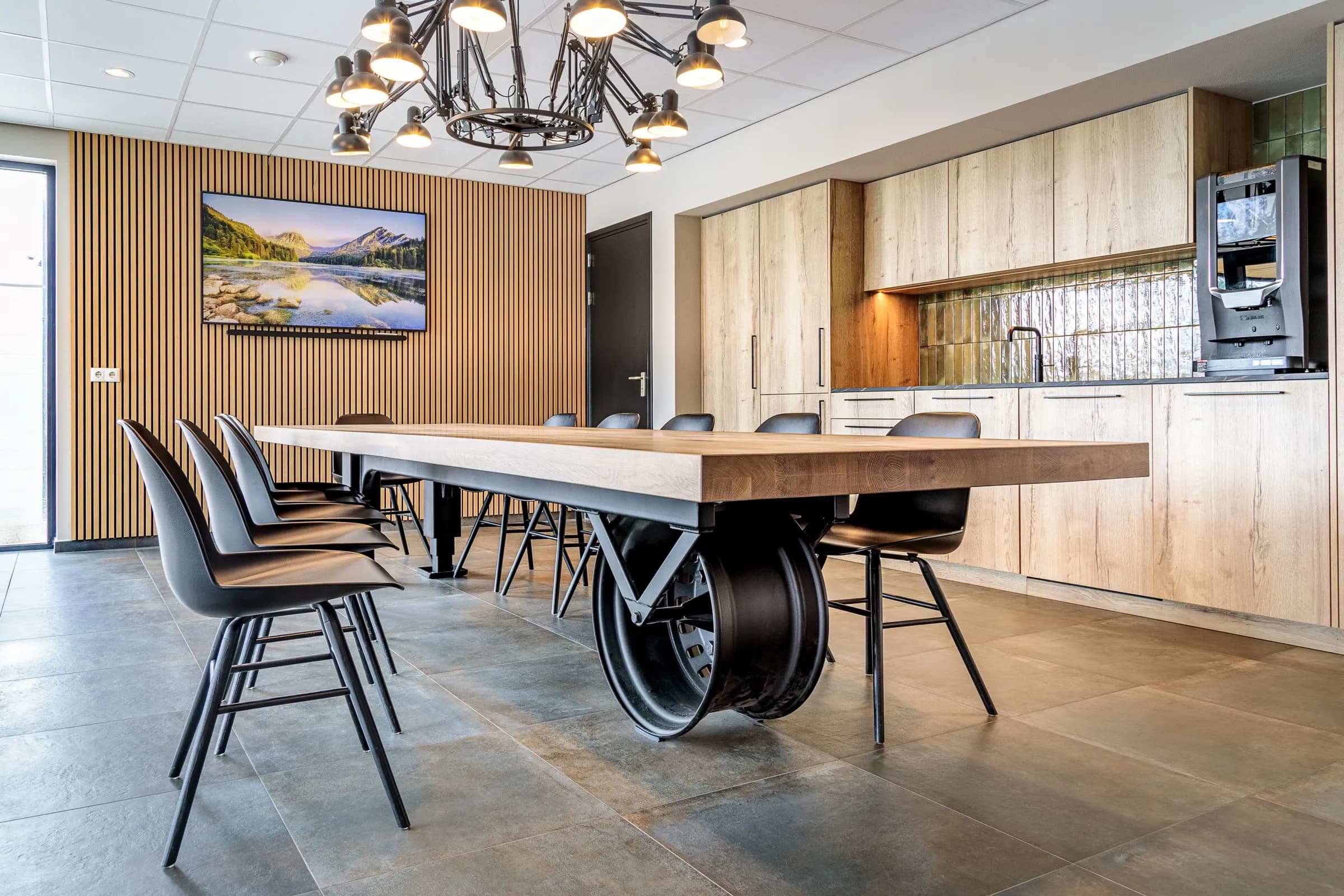 Long table on a black wheel base with black chairs in a canteen with a wooden slat wall
