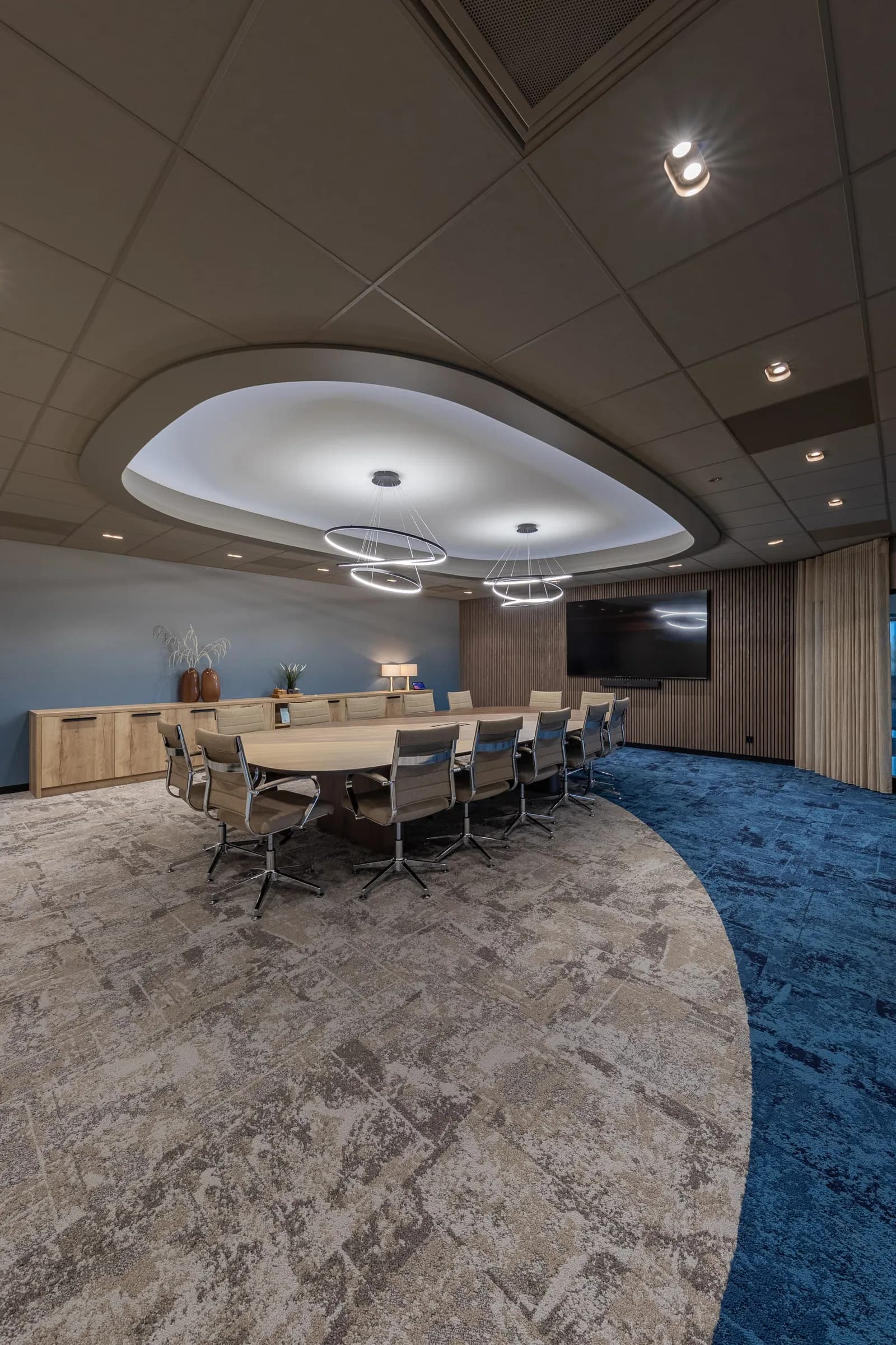 Boardroom at Kramer Seafood with an oval table, grey chairs and a ring light above a blue carpet