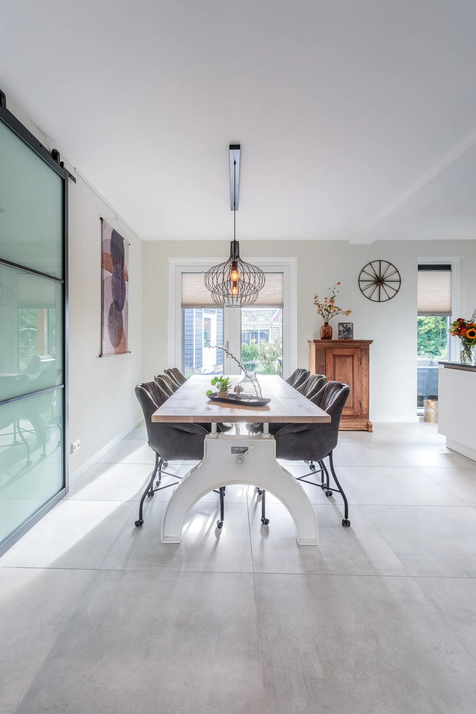 Long oak dining table on a white steel column base with grey chairs in the Loosman family home
