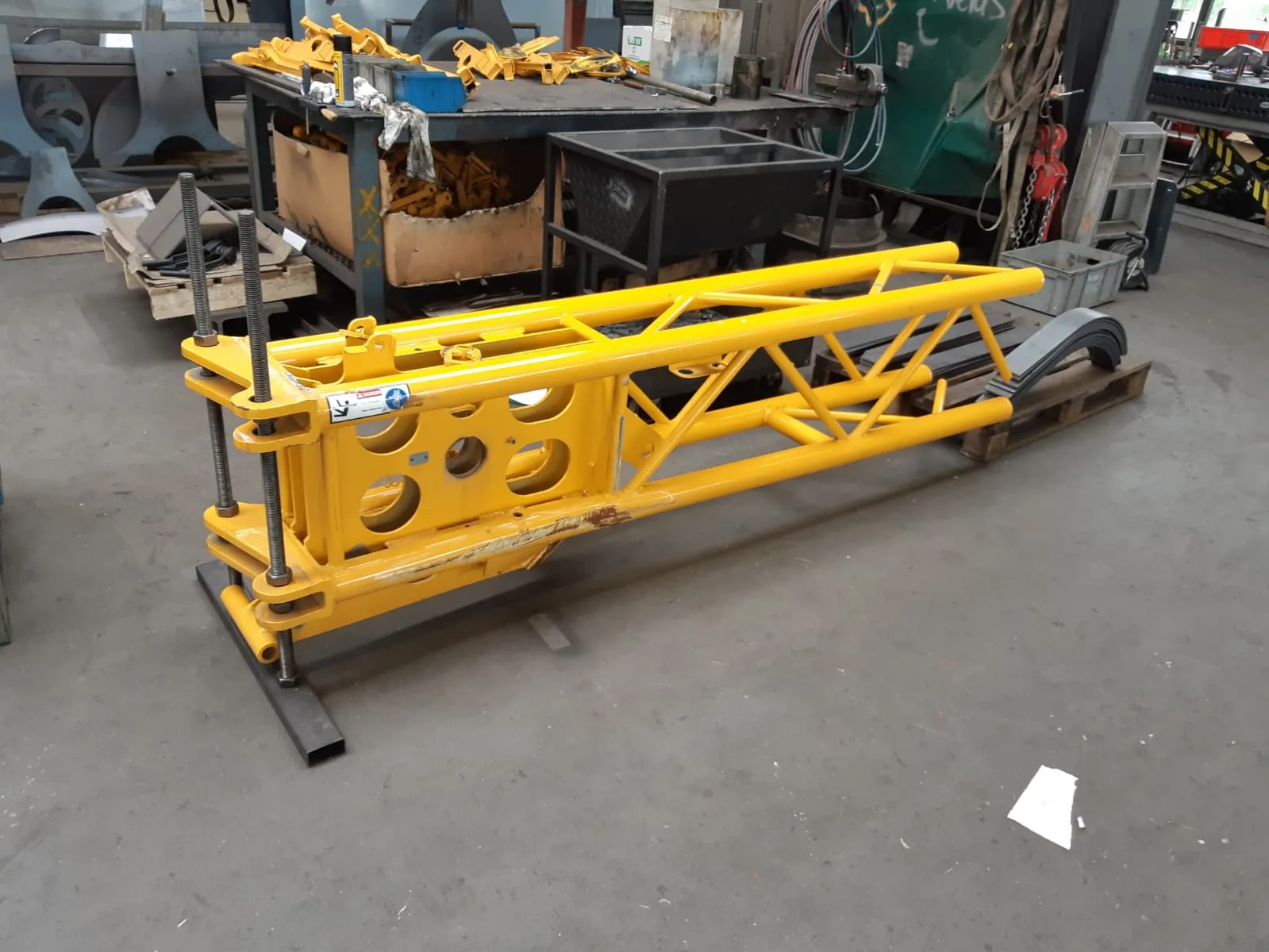 Yellow crane jib section in the workshop, reused as a table base