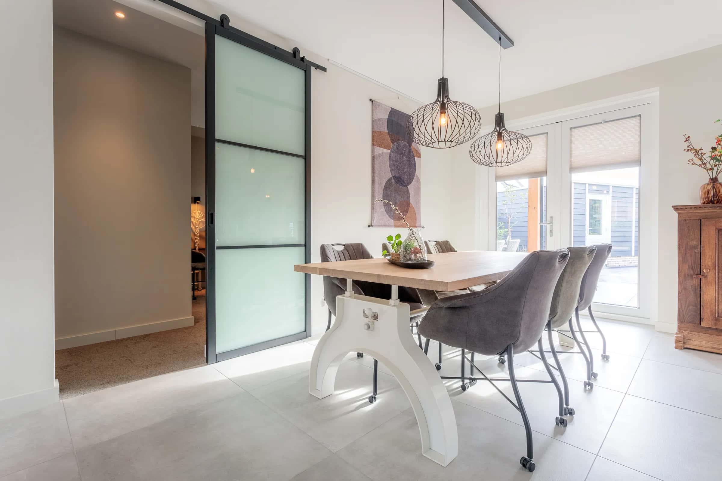 Long oak dining table on a white steel column base with grey chairs in the Loosman family kitchen