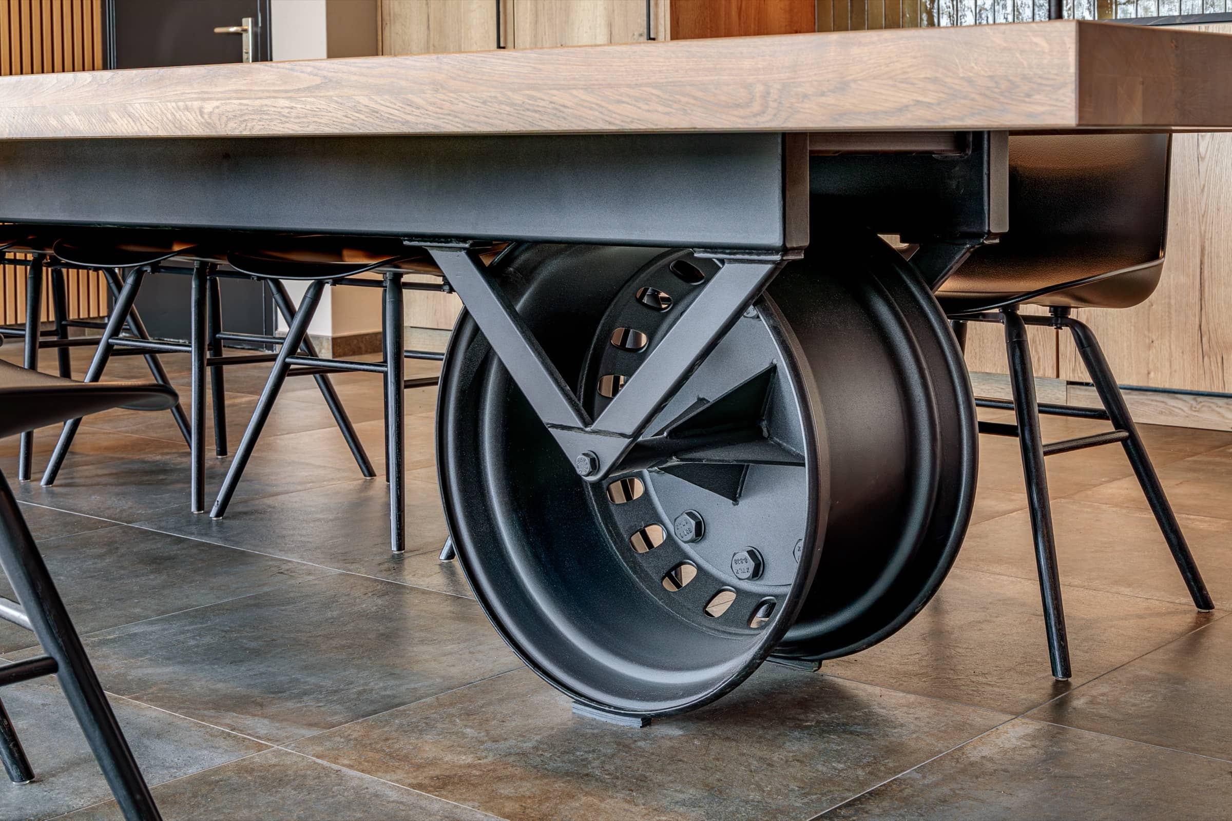 Stalen onderstel met een vrachtwagenwiel onder een eikenhouten maatwerktafel